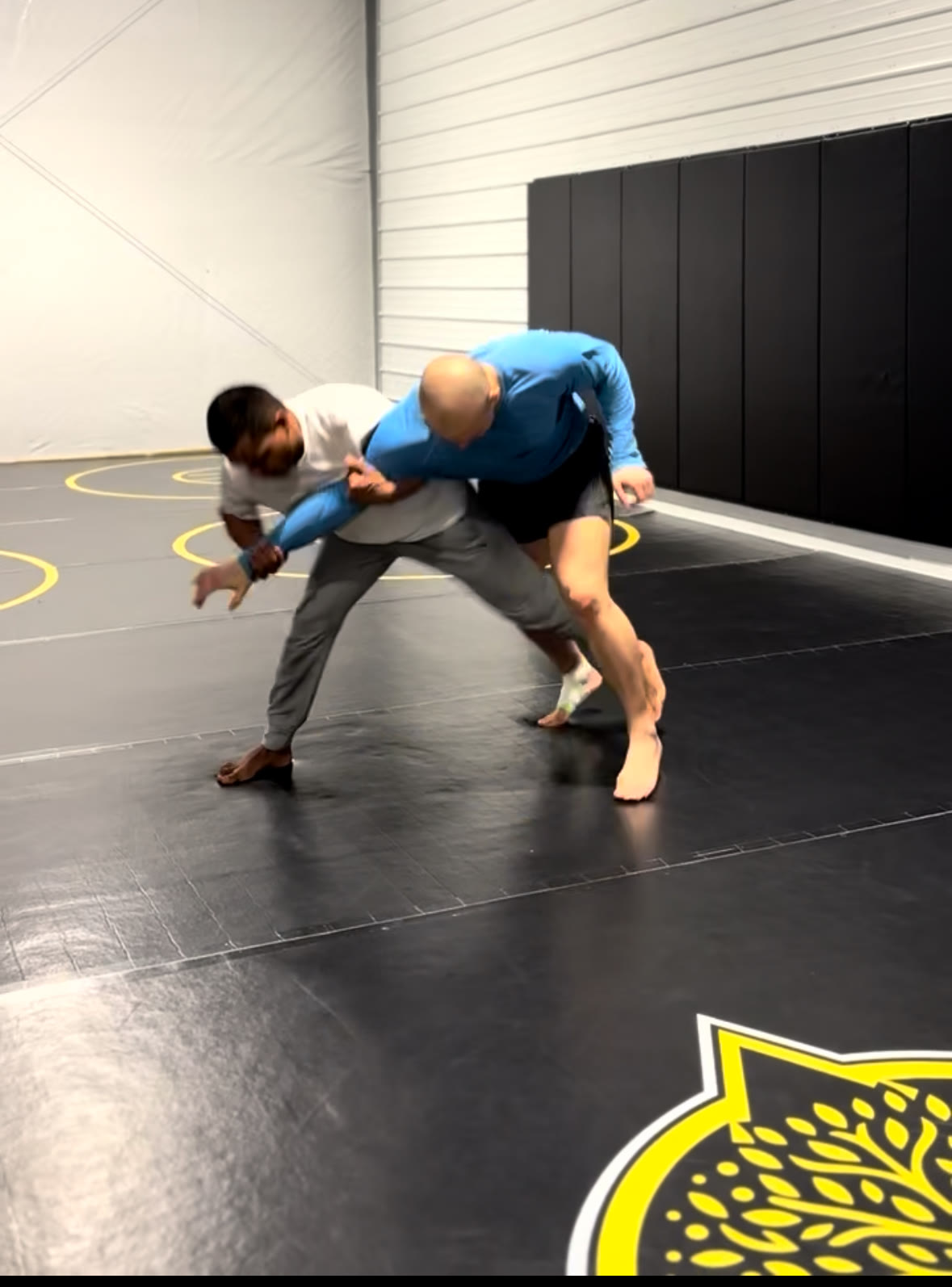 Two wrestlers locked up in a standing scramble during training at Golden Oak Combat Club